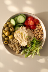 Top view of colorful Buddha bowl with quinoa, hummus, chickpeas, vegetables. Healthy vegetarian dish