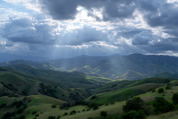 Naklejka premium Sunbeams Illuminate Rolling Green Hills and Mountains Dramatic Cloudy Sky Landscape Photography rolling hills