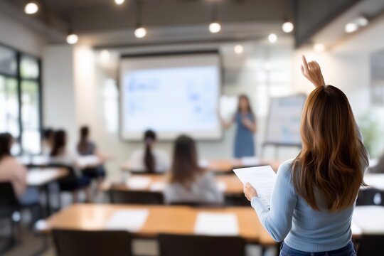 A student raises her hand in a modern classroom, indicating active participation during a presentation