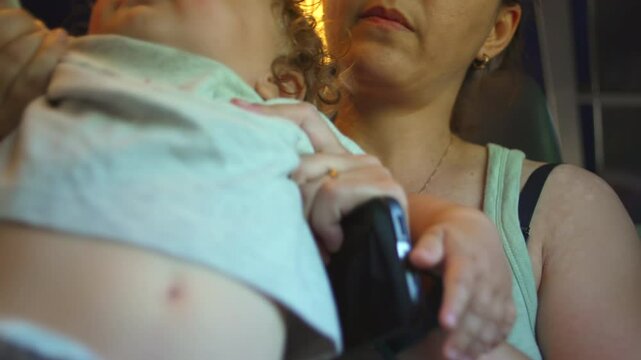 Mother sets phone aside and lifts baby closer during train ride, shifting attention from screen to child in quiet moment of reconnection