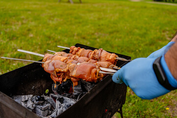 Outdoor BBQ process: Person grilling fresh meat kebabs on charcoal mangal. Perfect for summer...