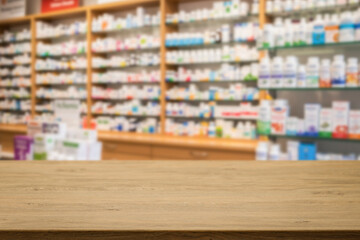 Empty wooden counter with copy space in front of blurred pharmacy shelves with medicines....