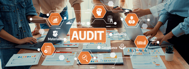 Professional team engaged in an audit process using laptops and digital tools, focusing on...