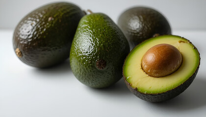 Fresh avocado cut in half, showing smooth green flesh and large seed against a white background.
