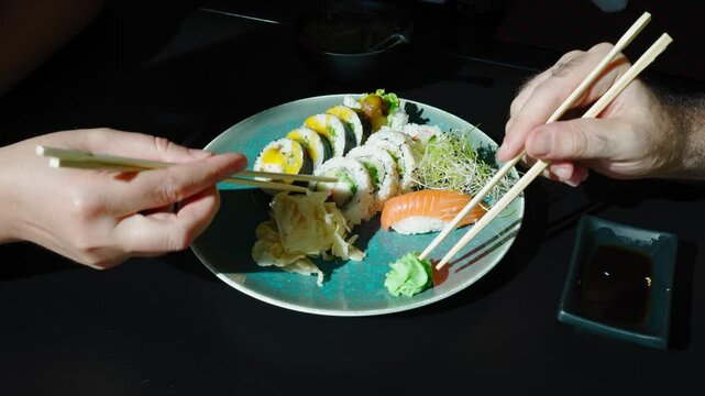 They take sushi with chopsticks, eating sushi plate, fish maki rolls, japan seafood, sushi set, asian dinner, tradition nigiri susi in japanese restaurant