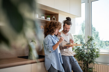 Young couple enjoying sushi together in modern kitchen