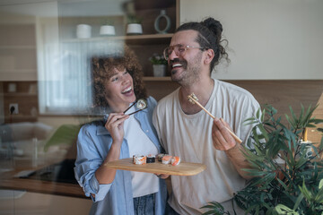 Happy couple enjoying sushi in modern kitchen