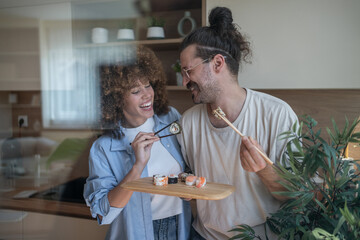 Happy couple sharing sushi in modern kitchen