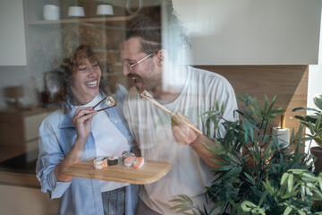Happy couple eating sushi in modern kitchen
