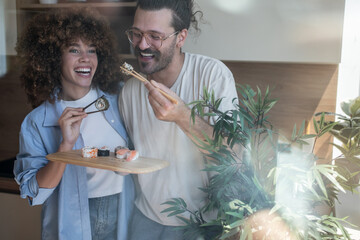 Happy couple enjoying sushi together in modern kitchen