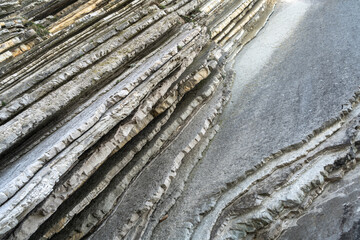 Layered rocks, flysch texture background. Sedimentary rock, striations stone pattern