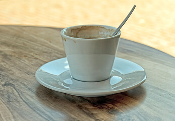cup and saucer with spoon standing on a round wooden table