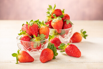 Strawberries, glass jars with beautiful strawberries on a white rustic wooden surface, abstract background, selective focus.
