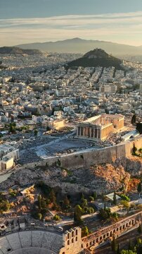 Fly over Parthenon in Athens in the morning, Ancient Greece landmark. Aerial view of Athens, Greece at sunrise, showcasing Acropolis and surrounding city. Vertical shot