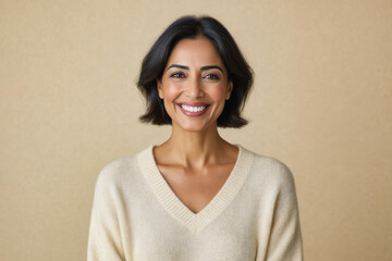A smiling woman with dark hair and fair skin gazes directly at the camera, radiating confidence in a soft-lit portrait.