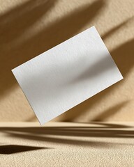 Fototapeta premium A blank white card is displayed with shadows and sunlight