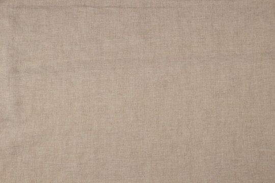 Textured linen background in soft beige color. Natural linen fabric material texture background. Top view
