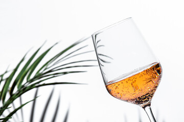 Refreshing rose pink wine served in a glass against a minimalistic background with subtle palm...