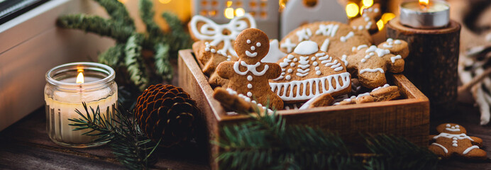 Banner. Wooden box with homemade delicious gingerbread cookies decorated with white icing. Handmade zero waste gift for Christmas or New Year. Cozy home atmosphere, fairy lights, fir tree branches