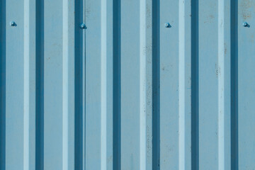 Blue corrugated metal wall with bolts. Abstract background with texture and vertical stripes for industrial design.