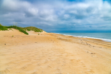 Sandy shore under a cloudy sky by the Atlantic Ocean.
