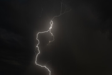 Dramatic thunderstorm illuminates the night sky over rooftops during a powerful lightning display