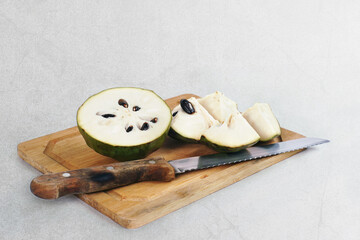 cherimoya (Annona cherimola) or Custard apple in cutting board on a textured grey background