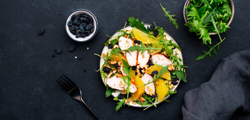 Winter salad with grilled chicken fillet, orange slices, raisins, walnut, arugula, spinach and useful seeds
