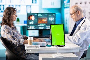 Senior medic consulting ill woman in cabinet with isolated mockup screen, checking the hospital...