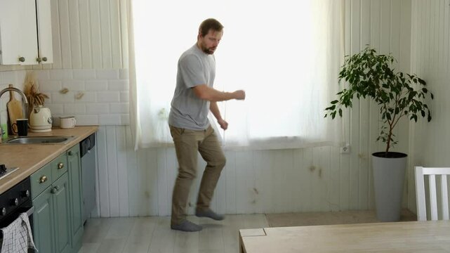 Handsome bearded man dance, have fun at home listens song, moves to music, feels overjoyed, celebrate good news, relish carefree life looks happy. Young adult male twirls, grooves. Brutal man dancer