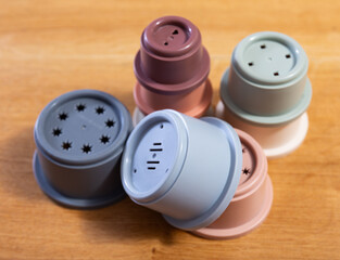 Array of multicolored plastic cups of disassembled pyramid scattered on wooden table, perfect for engaging children sensory and motor skills