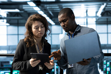 System administrators in data center using devices, executing security patches, verifying firewall...