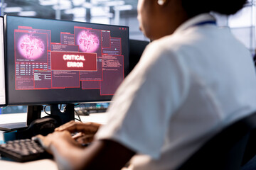 Computer scientist in server hub investigating breach alerts, working to protect infrastructure from hacker. Worker typing on PC keyboard, fixing critical error, trying to mitigate security risks