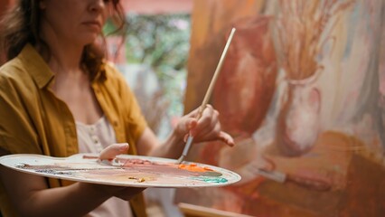 Talented artist painting artwork with colorful paints mixed on palette, creating beautiful creative...