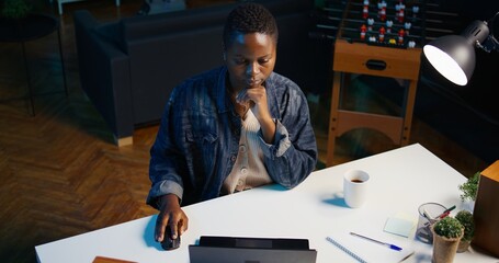 Woman in living room office using laptop to answer emails from business partners, drinking coffee....