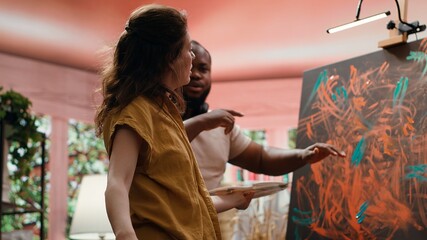 Talented artist and her apprentice engage in finger painting hobby in art and craft workshop, using...