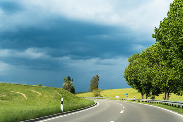 A curved road under a dramatic sky with incoming storm clouds.