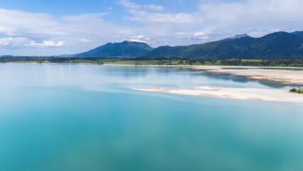 Puffy clouds gather above still lake waters and distant mountains.