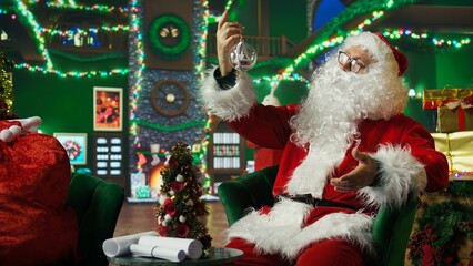 Santa Claus admiring beautifully crafted Christmas tree globe, surrounded by stockings, fake...
