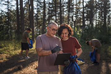 husband and wife volunteer during cleaning forest review clipboard