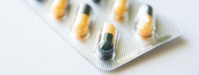 Yellow and black capsules in packaging, representing healthcare and medicine. Photo. High resolution. Selective focus