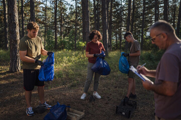 family of volunteers men woman pick up waste garbage to clean forest