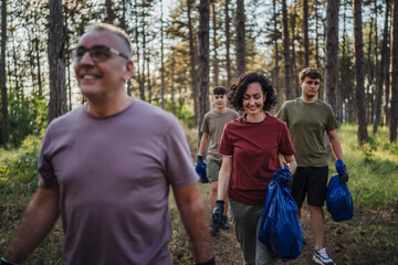 family of volunteers pick up waste garbage and walk through from forest