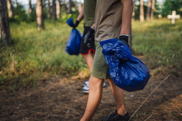 unknown volunteers pick up waste garbage and walk through from forest