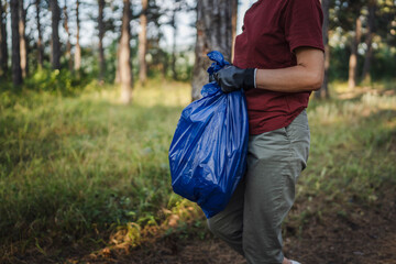 unknown volunteers pick up waste garbage and walk through from forest