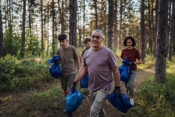 family of volunteers pick up waste garbage and walk through from forest