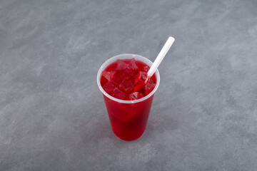 Agua de Jamaica or Jamaica drink. Trendy refreshing summer ice drink in disposable plastic cup. Red hibiscus ice tea. Karkade chai with ice cubes