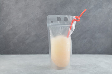 Refreshing citrus granizado or lemon iced slushie drink in spill-proof drink pouch with drinking straw. Sweet fruit shaved ice. Frozen summer non-alcoholic cocktail in plastic bag