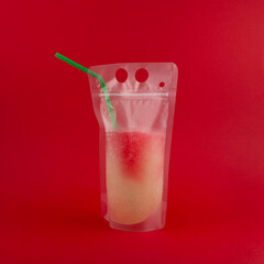 Frozen Slush Drink in plastic bag on red background. Grapefruit Lemon Granizado. Spill-Proof...