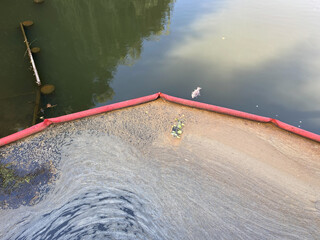 Flexible dam or barrier for floating debris. Protecting river from pollution. Dirty foam, garbage...